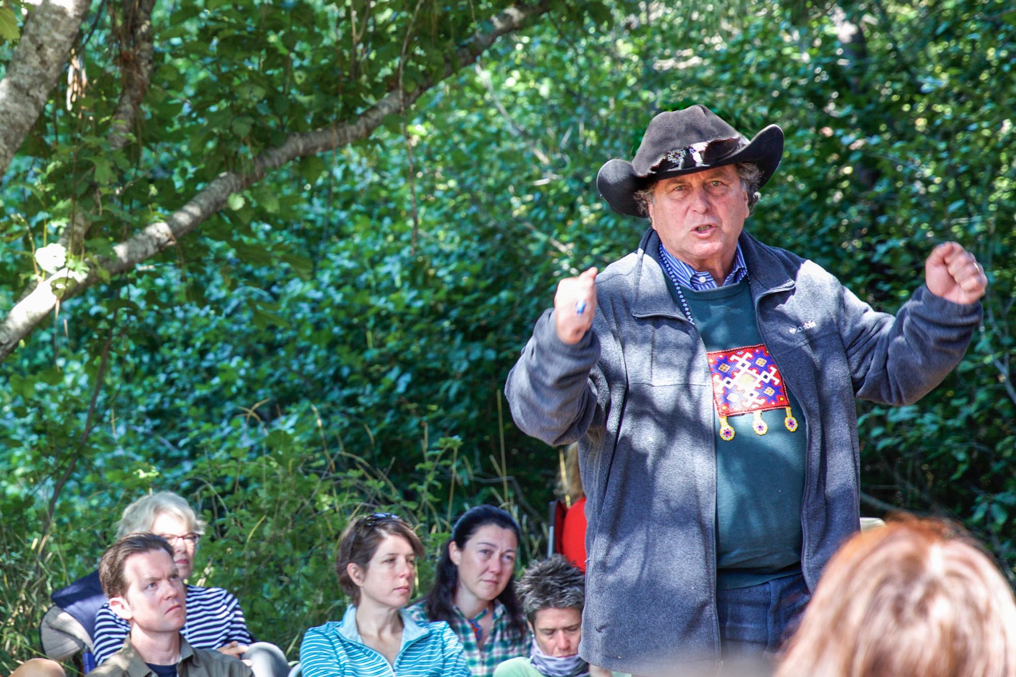 Brant Secunda speaks to a crowd of people in nature